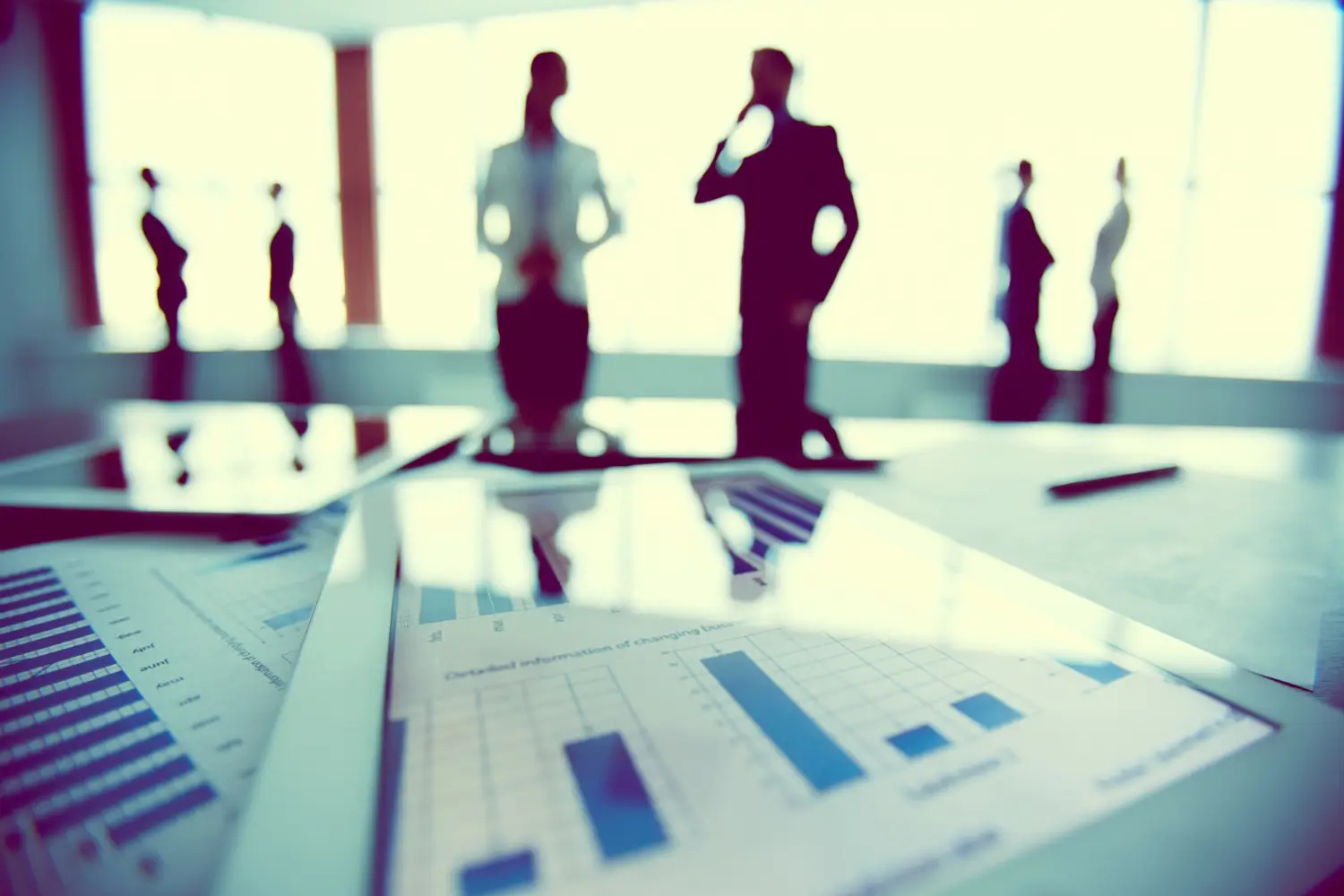 chart on table with people discussing in the background chart on table with people discussing in the background