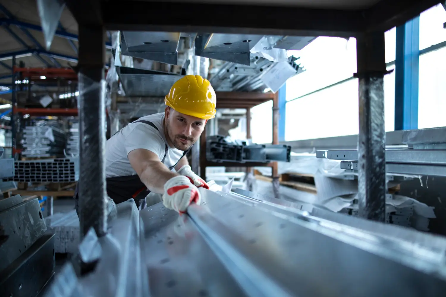 worker with hardhat on and milling metal building product