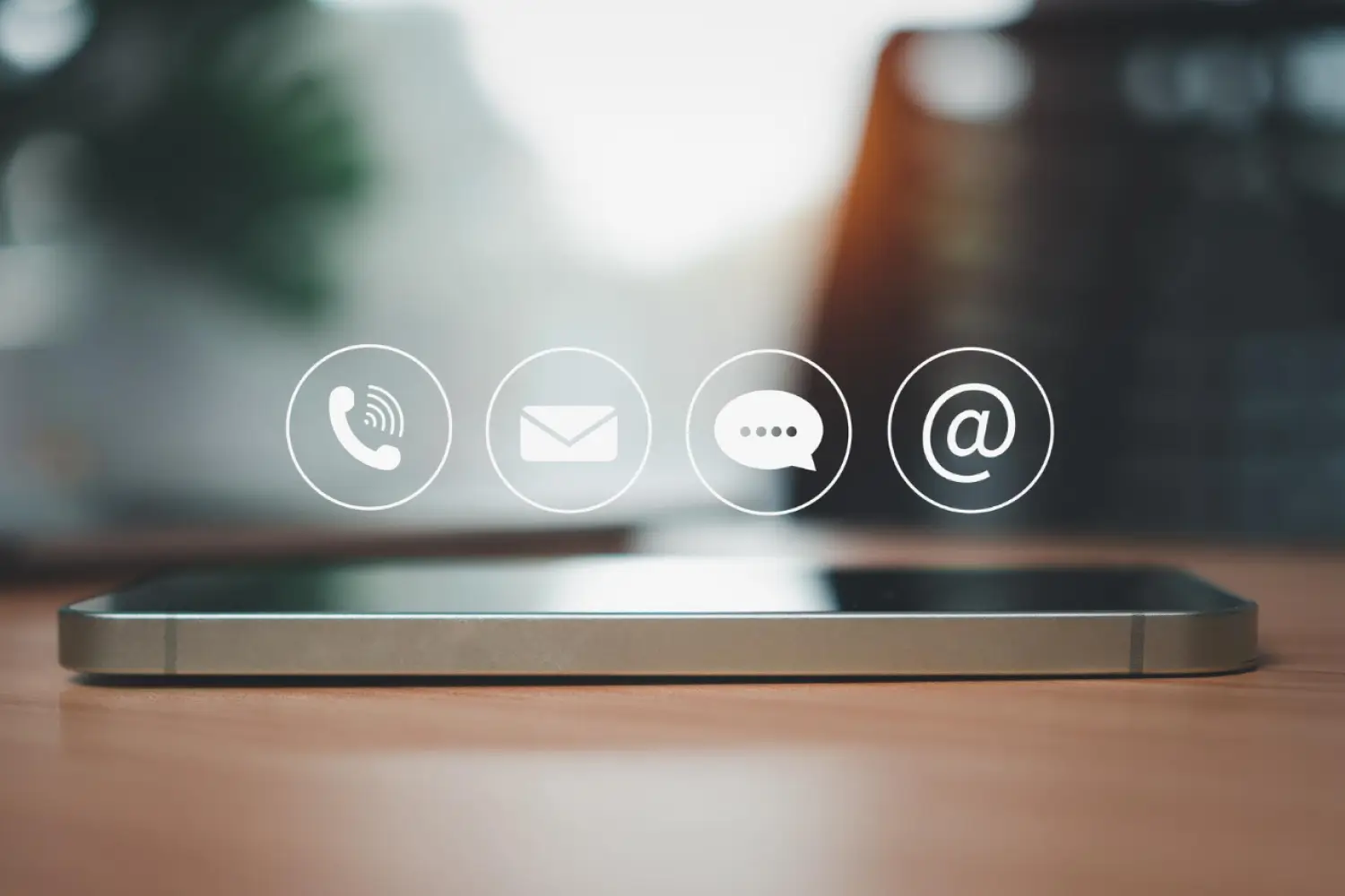 mobile phone on table with phone, mail, message, and at symbol above it mobile phone on table with phone, mail, message, and at symbol above it